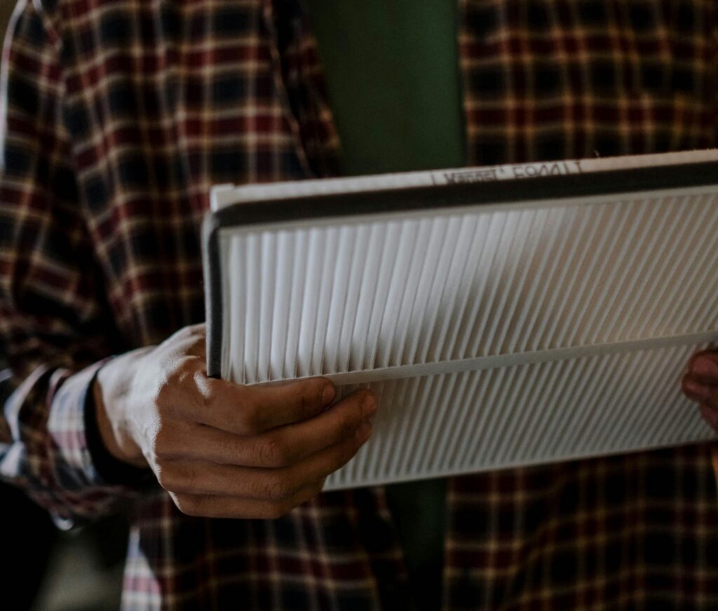 Homeowner inspecting an HVAC air filter as part of maintaining indoor air quality