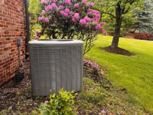 Outdoor AC condenser unit surrounded by spring landscaping ready for seasonal HVAC tune-up