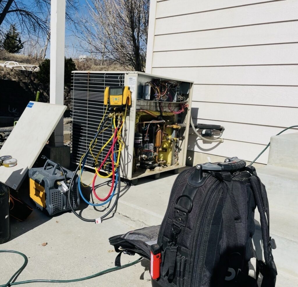 AirCare Heating & Cooling technician testing an outdoor AC unit during an emergency AC repair in Richland, WA 