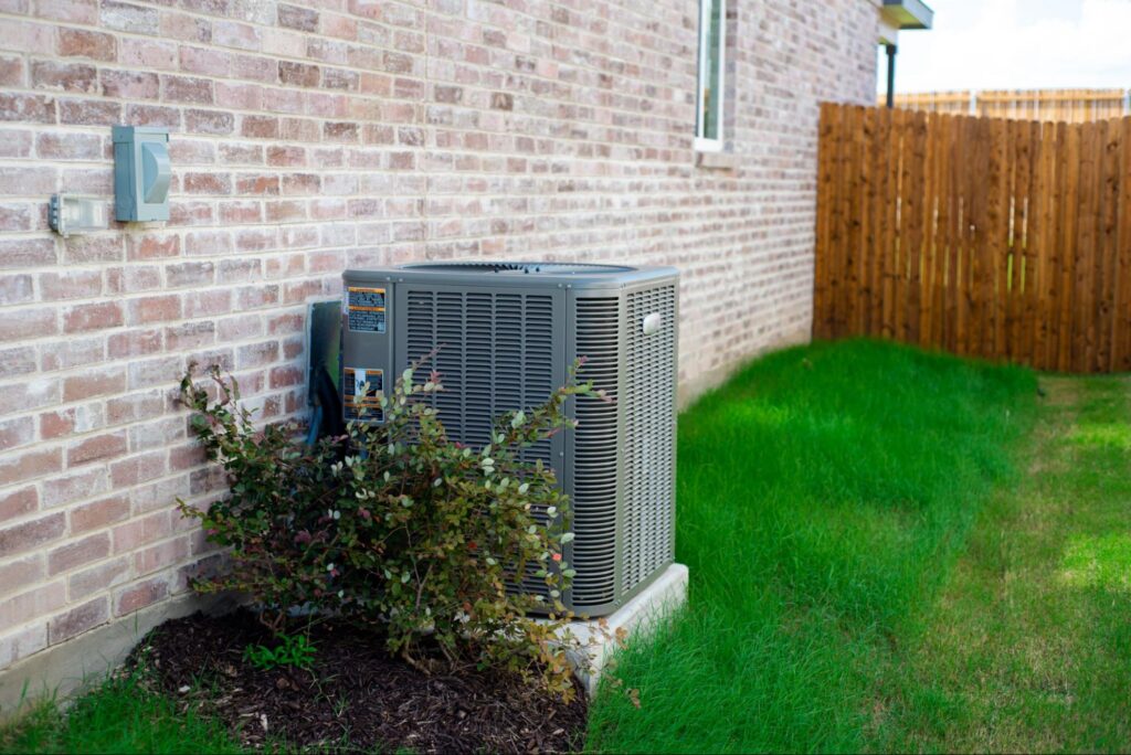 Outdoor AC condenser at a Finley, WA home with shrubs crowding the unit's airflow